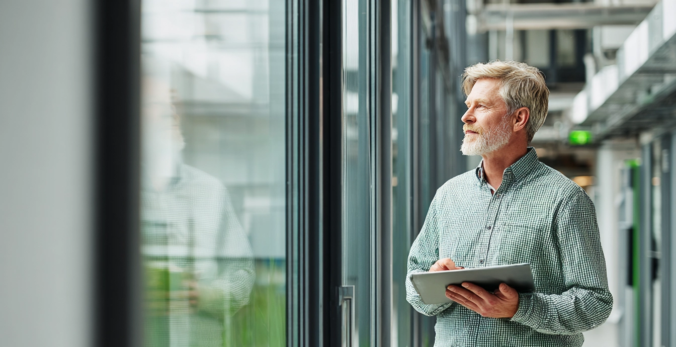 Ammattilainen seuraa energiatehokkuutta modernissa työympäristössä, korostaen ympäristöjärjestelmän käytännön säästökeinoja.
